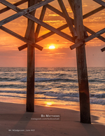 landscape photography of a sunrise through pier pilings